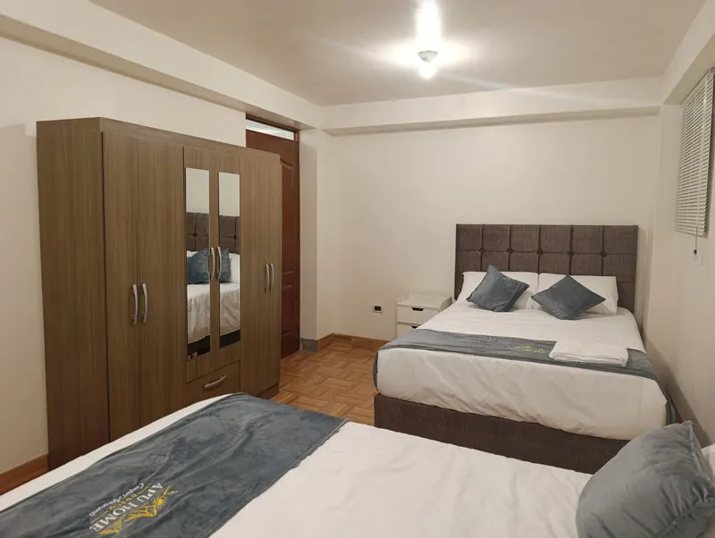 Dormitorio con dos camas, cabeceras tapizadas y ropero con espejo