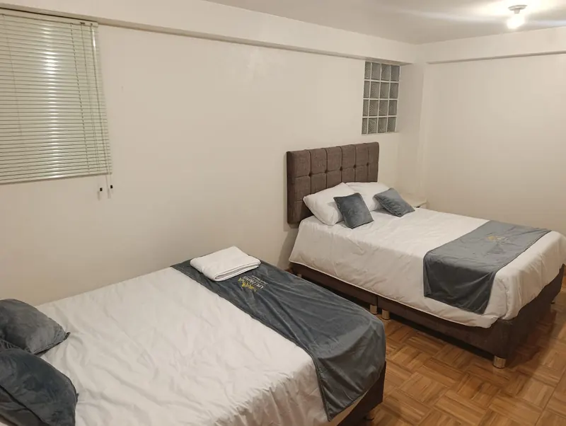 Dormitorio con dos camas, ropa de cama blanca y toallas dobladas